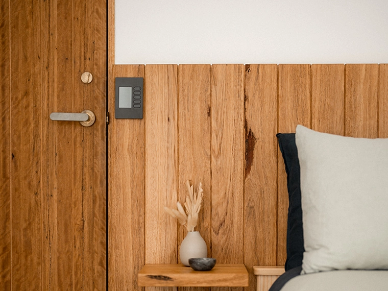 SpaceLogic C-Bus control panel mounted on a wooden paneled wall.