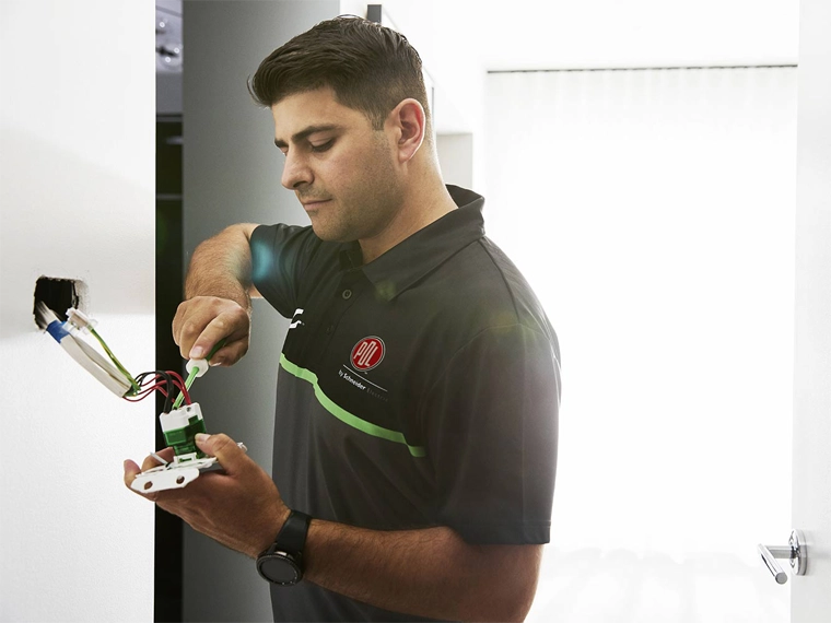 An electrician in a PDL branded shirt installing Wiser Smart Home products.