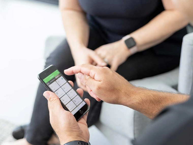 A pair of electricians using the Wiser by SE app on a smartphone.