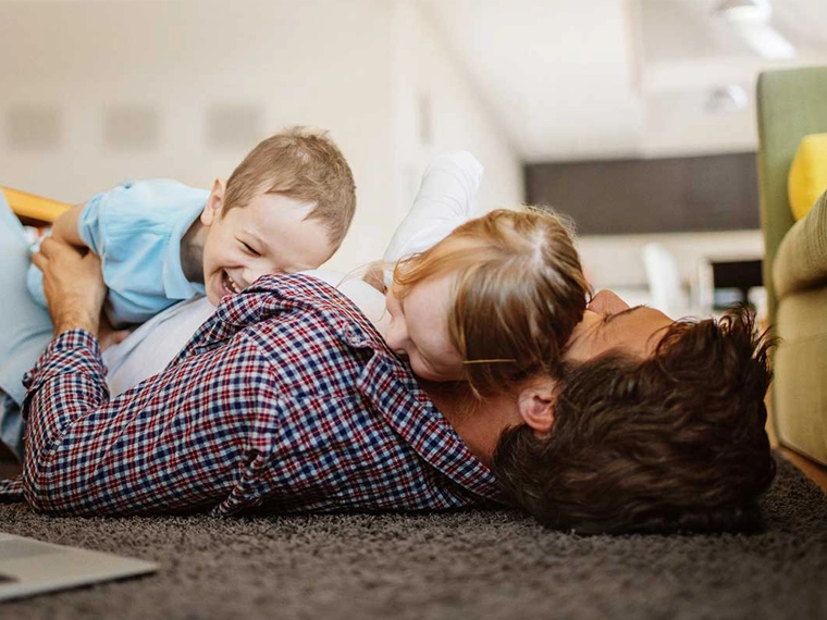 A family laughing while lying down together on the floor.
