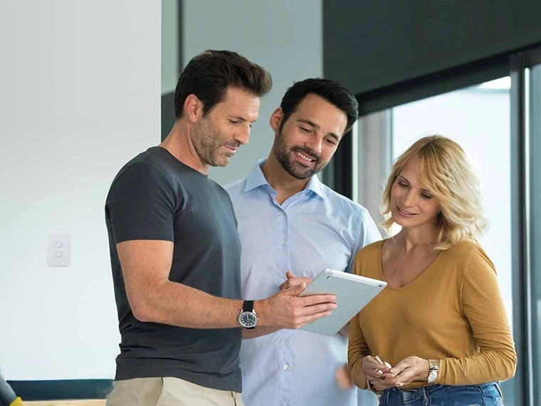 Three people reading an article on a tablet.
