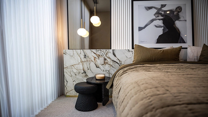 Home renovation project featuring a modern bedroom with an Iconic Styl cover plate in a marble accent wall, pendant lighting, abstract artwork, and a cozy bed with textured bedding.