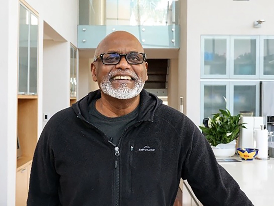 Des Dass smiling in his home.