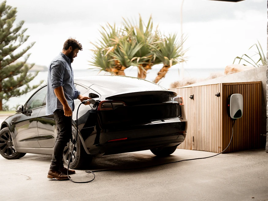 Neil plugs an EVlink home charger into an electric vehicle at Bunker House.