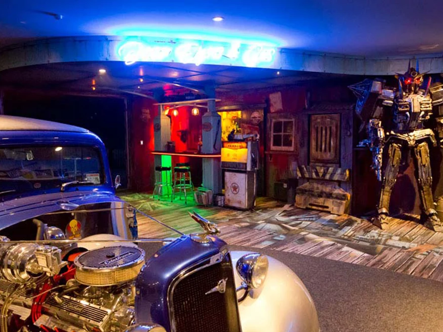 Wayne and Aimee’s showroom and workshop, featuring classic cars and models of aliens and transformers.
