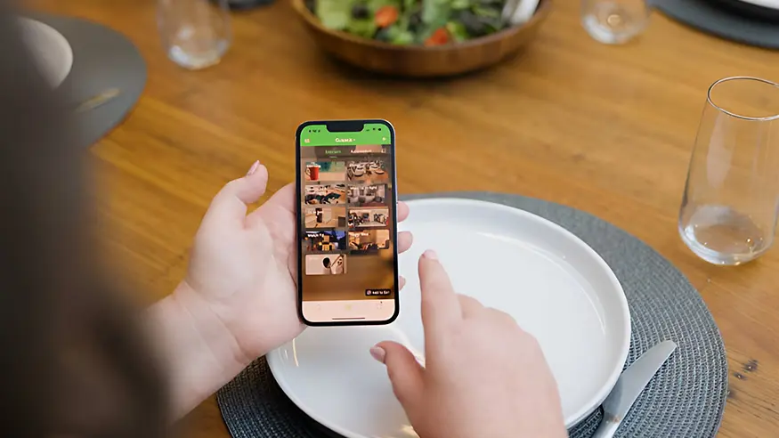 Person using Wiser by SE app on smartphone at a dining table.