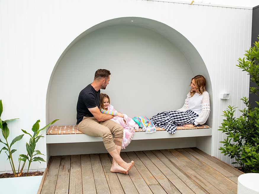 Family relaxes in a modern outdoor alcove with a sleek power point nearby.