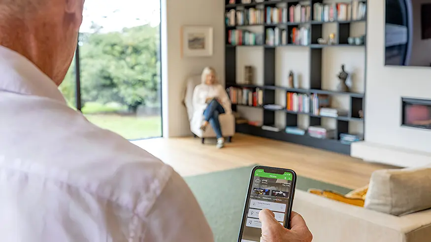 A homeowner using PDL Wiser Smart Home Automation on their phone.