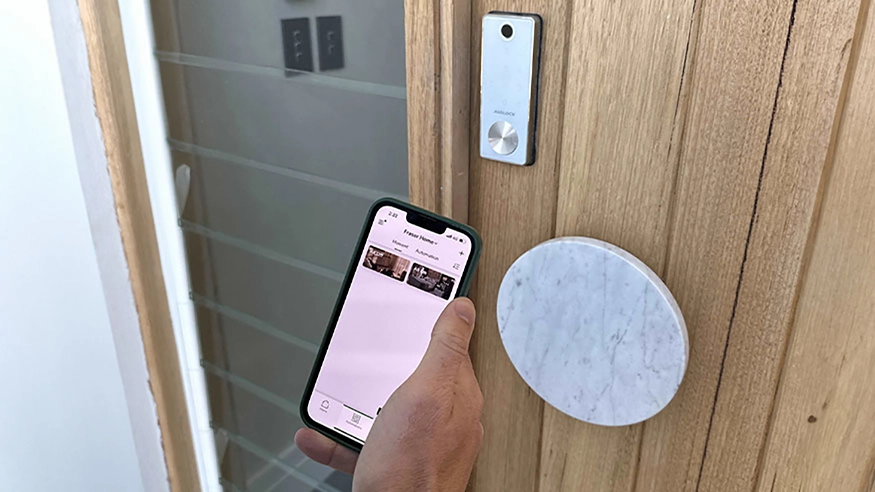 A homeowner controlling the light switch using Wiser by SE app on their smart device.