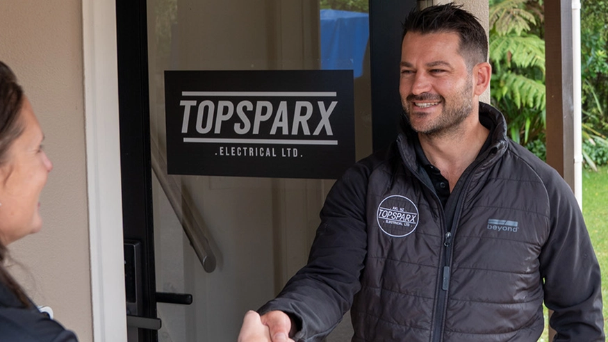 An electrician from Top Sparx Electrical smiling and shaking hands with a client.