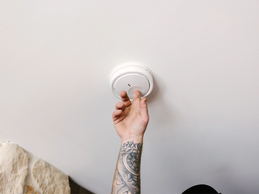 A round PDL Wiser Smart Smoke Alarm being installed.