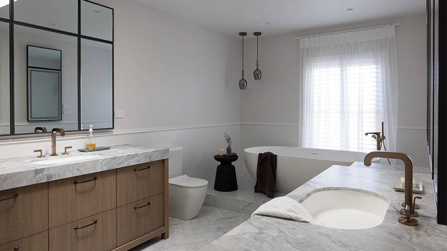 Contemporary bathroom with marble countertop, freestanding tub, and pendant lighting. Features Clipsal Iconic switch besides the large mirror.