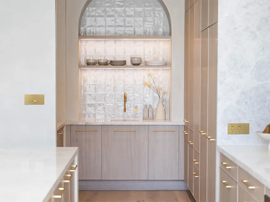 Clipsal Solis Switch in brushed brass aluminum on a kitchen wall with white countertops.