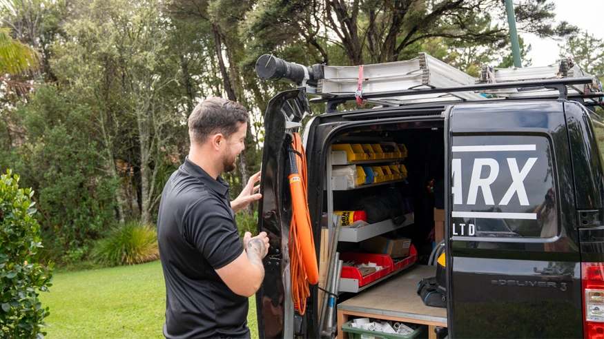 An electrician from Top Sparx Electrical inspecting his work van.