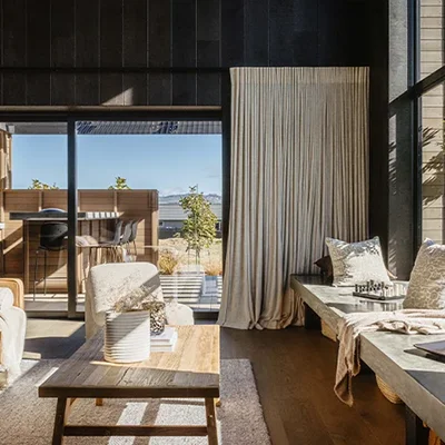 A bright living room with a comfortable couch, a coffee table, and windows that provide a view of the outdoors.