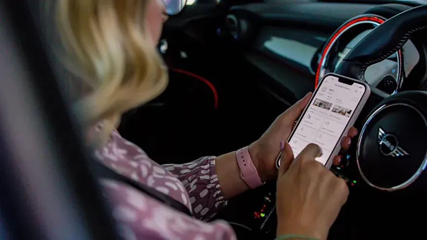 Michaela using PDL Wiser on her phone while sitting in her car.