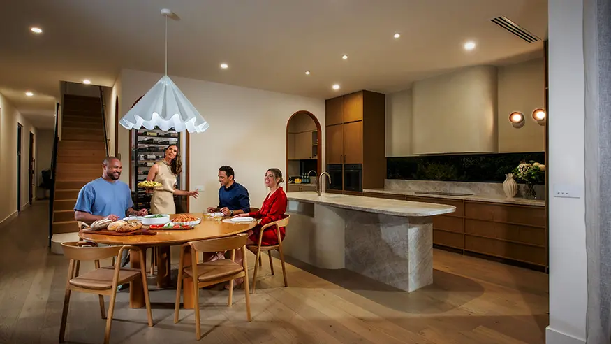 Brad and Tess with family in their home. Tess turns off a light with a Solis T Series switch.