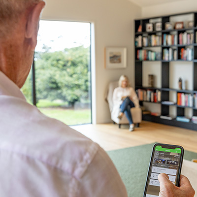 Man adjusts dining room lights with Wiser by SE app on smartphone