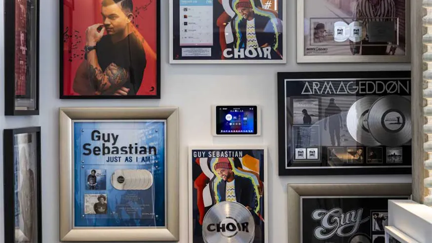 Wall display featuring Guy Sebastian’s framed awards and achievements, in the centre of it all is a C-Bus Display panel.