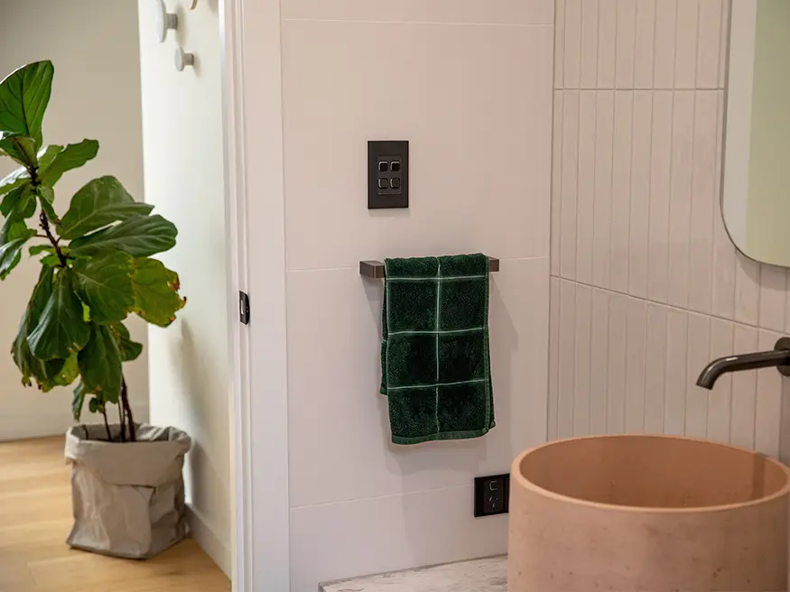 Iconic Styl switches and power points mounted on a tiled bathroom wall.