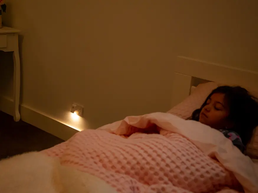 A young girl sleeps peacefully in a dimly lit bedroom.