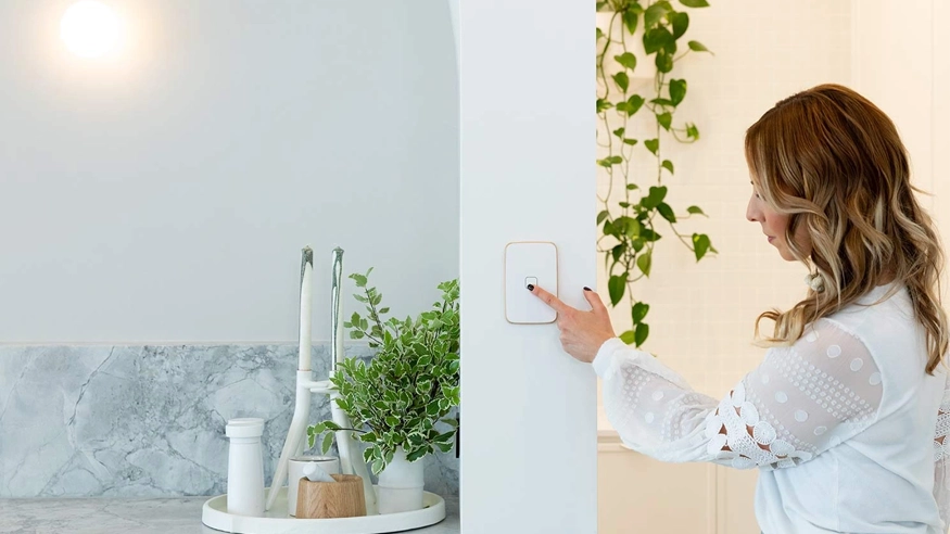 Woman presses the on button of Iconic Essence arctic white switch