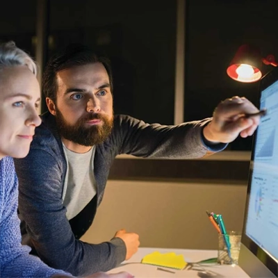 Two people reviewing information on a computer screen at a desk.