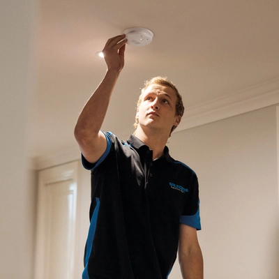 An electrician installing a Fire Tek smoke alarm.