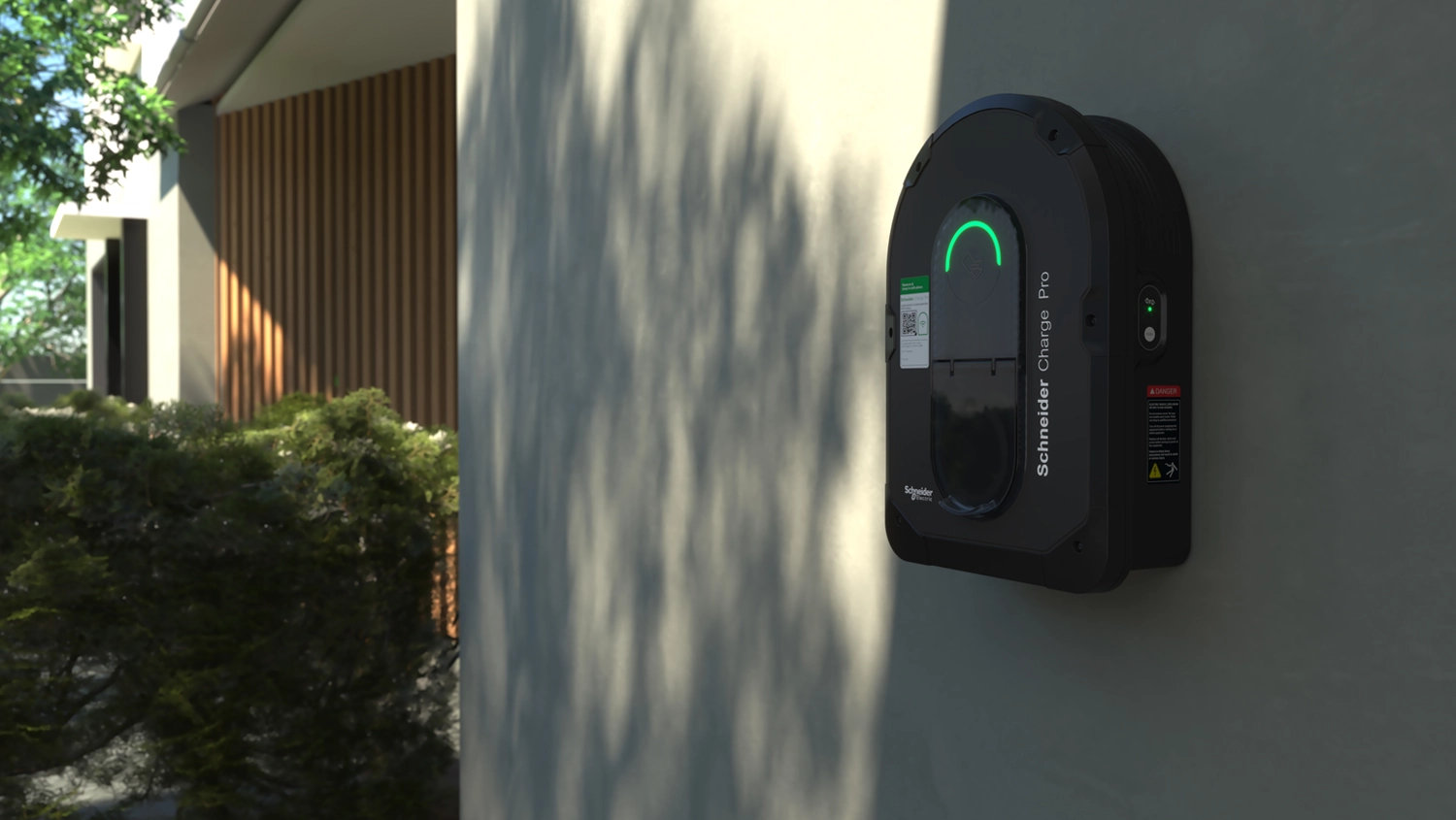 A Schneider Charge Pro EV charger wall-mounted on a white wall of a large modern house.