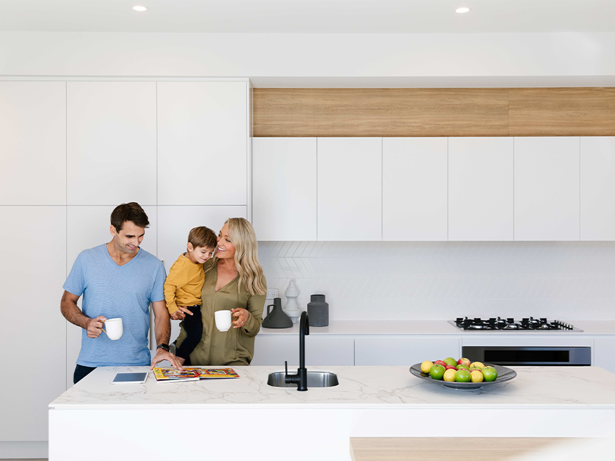 A family in a modern kitchen with a white countertop, enjoying each other's company