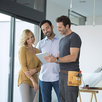 Man and Women looking at building plans, with builder.