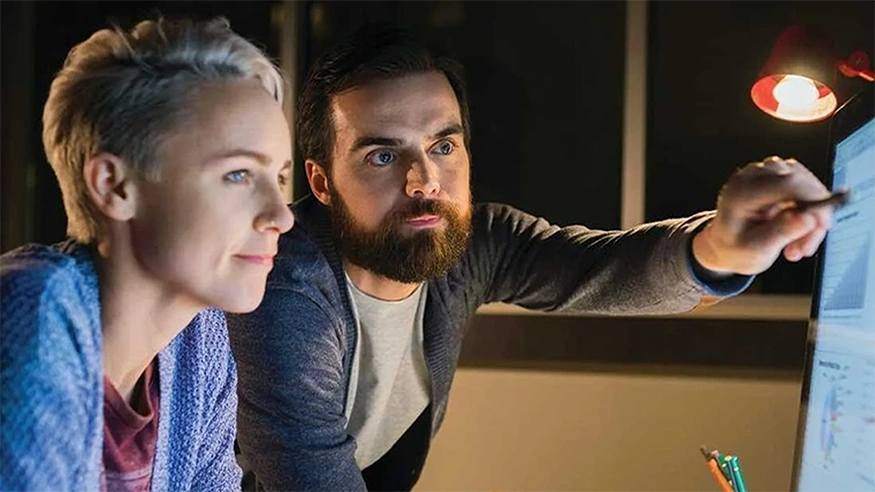 Two people completing an online training course on a desktop. 