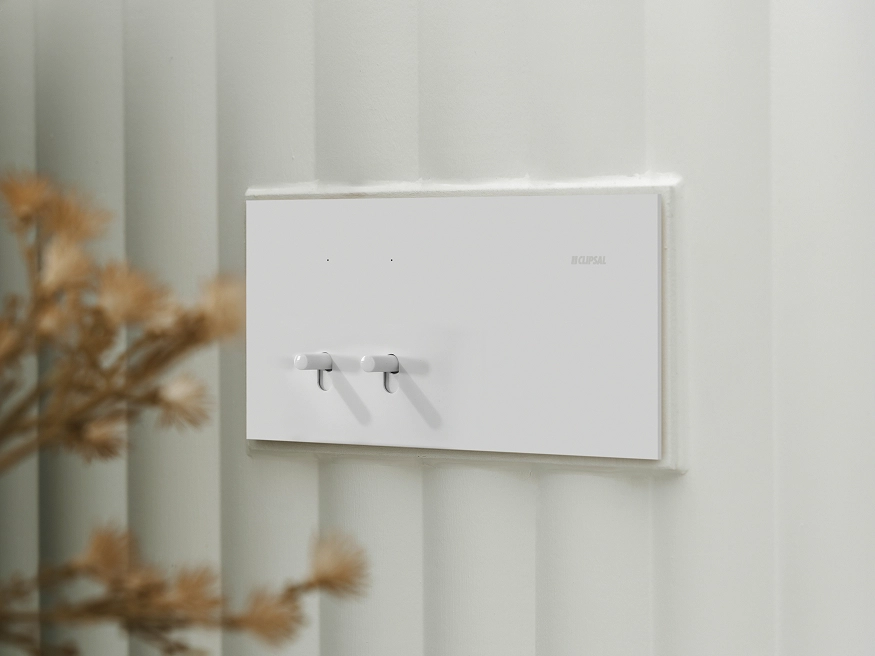 Clipsal Solis T Series Flush Switch in White Ceramic finish mounted on a textured light wall.
