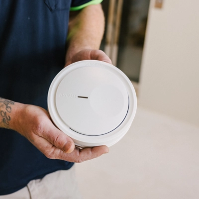 An electrician holding a PDL Fire Tek Smoke Alarm.