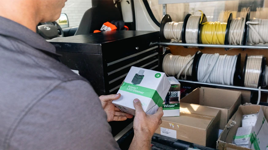 An electrician examining an Iconic LED dimmer product stored in the back storage of his electric car.